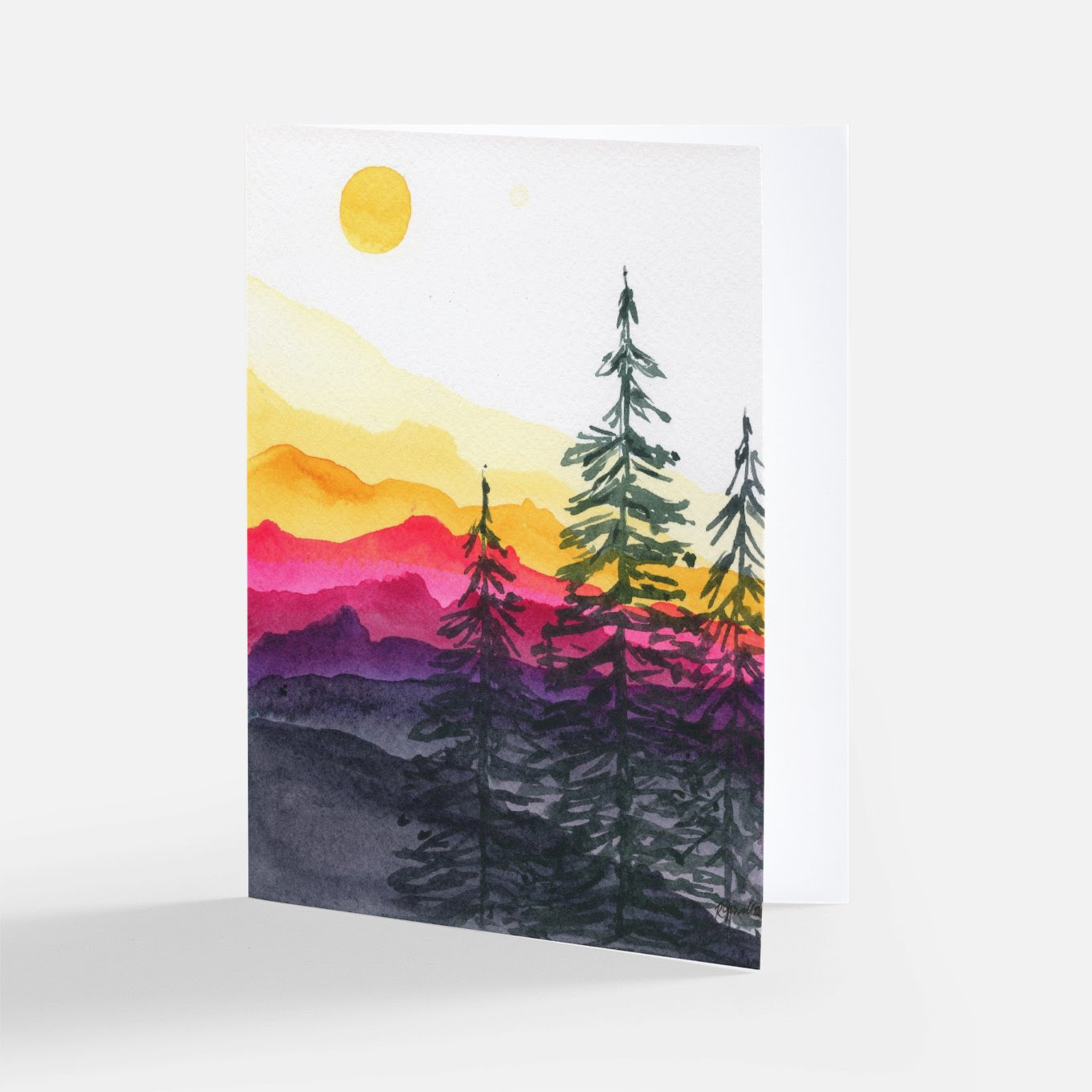 Watercolor notecard of layered yellow, pink, and purple mountains at sunset with tall dark pine trees and a yellow sun